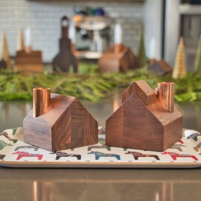 Deux petits chandeliers en bois avec des cheminées en cuivre sont posés sur un plateau sur un comptoir.