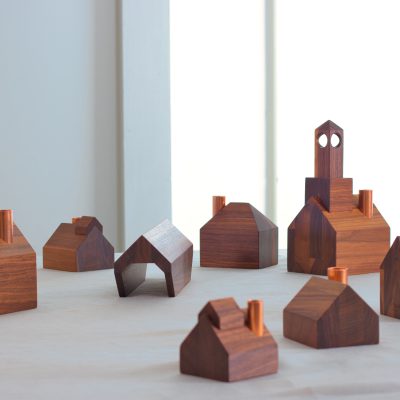 Un petit village de bougeoirs en bois dans une pièce blanche.
